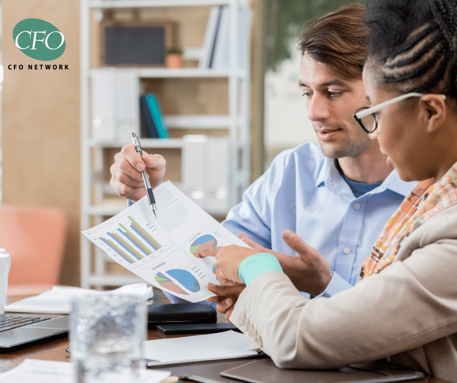 A man and a woman are sitting at a table looking at a piece of paper.