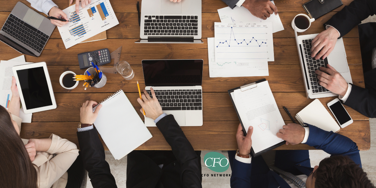 A group accountants are sitting around a table with laptops and papers.