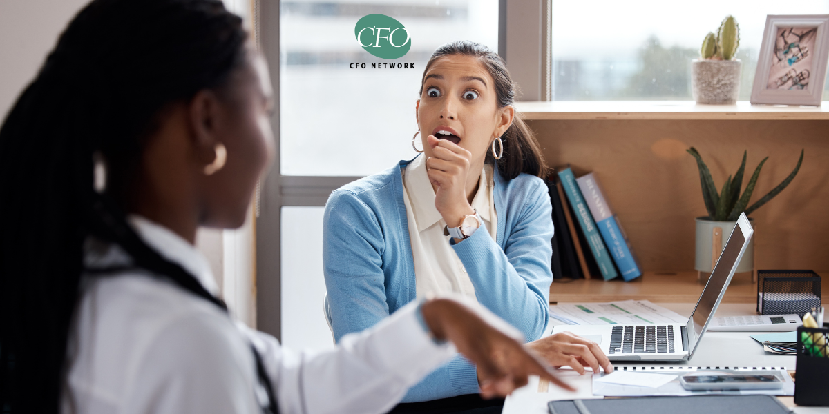 A woman is sitting at a desk with a laptop and talking to her accountant.