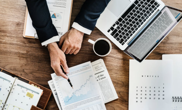 A man is sitting at a desk with a laptop and a cup of coffee discussing outsourced cfo services