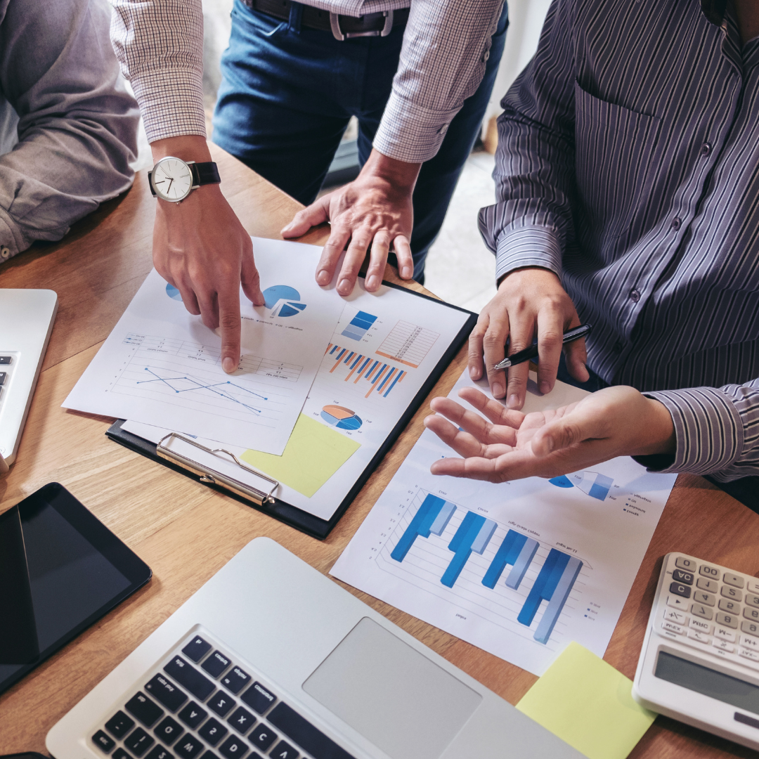 A group of people are sitting around a table looking at financial graphs