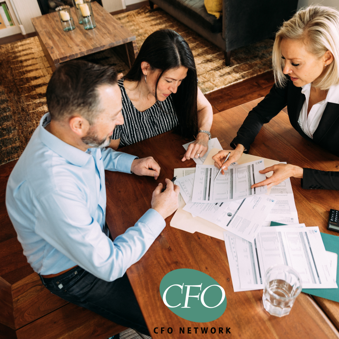 A group of people are sitting around a wooden table discussing selling their business.