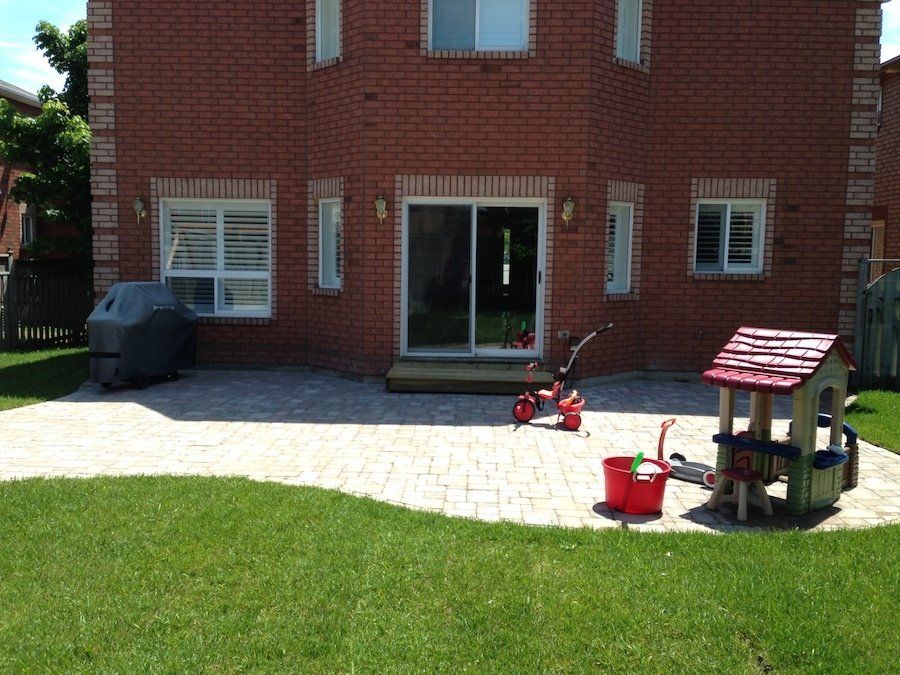 A brick house with a patio and a playhouse in front of it