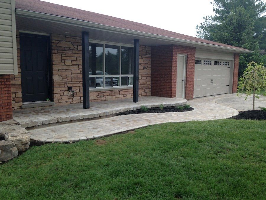 A brick house with a walkway leading to it and a garage.