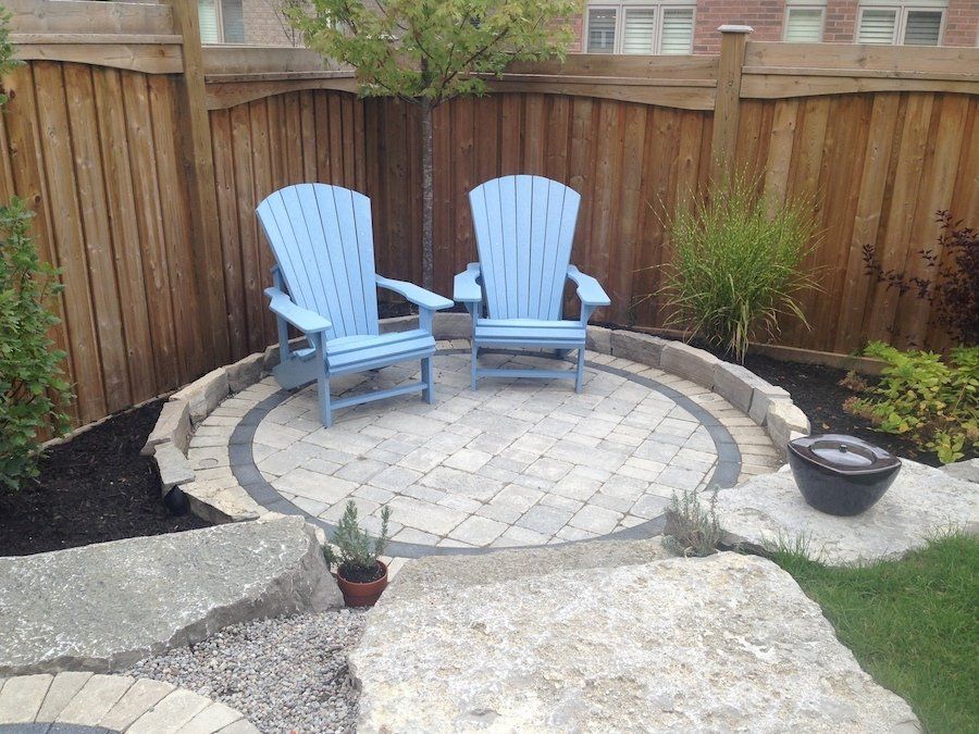 Two blue lawn chairs are sitting in a circle in a backyard.