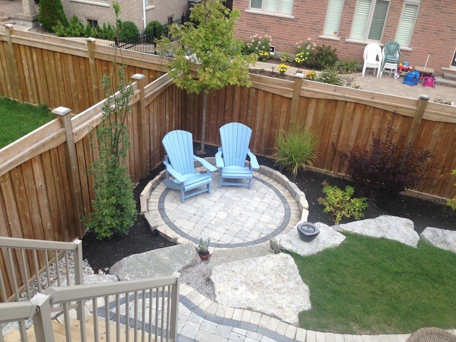 Two blue chairs are sitting in a circle in a backyard next to a wooden fence.