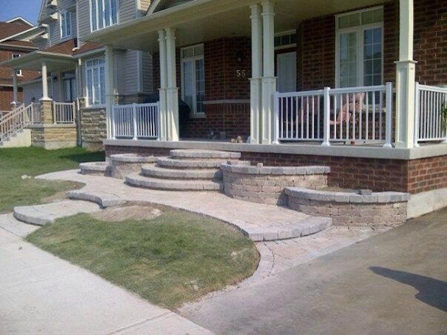 A brick house with a white railing and steps