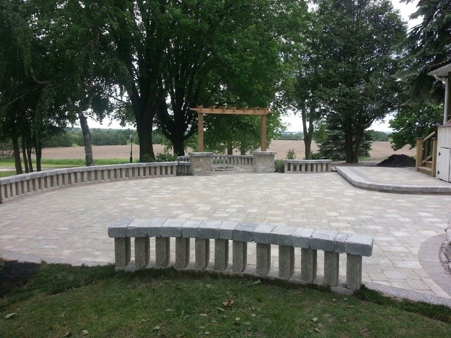 A patio with a bench and a pergola in the background