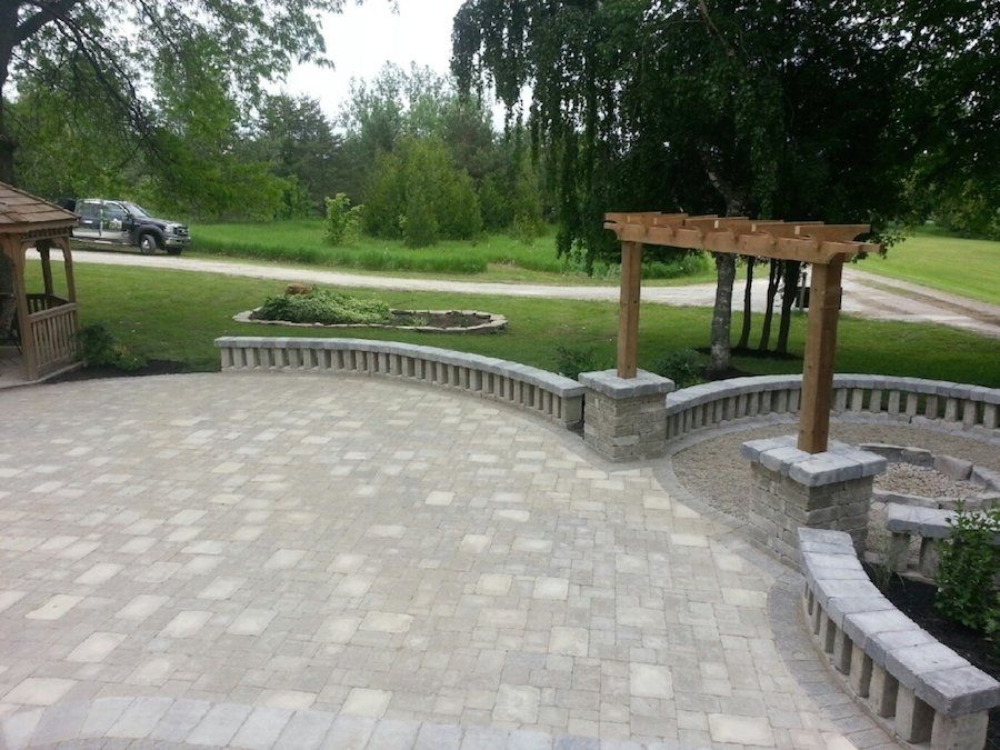 A patio with a wooden pergola and a car parked in the background