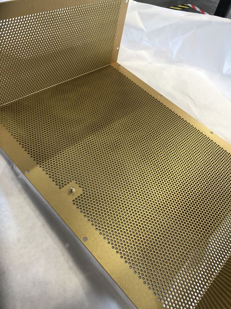 A perforated gold metal tray with a rectangular shape.