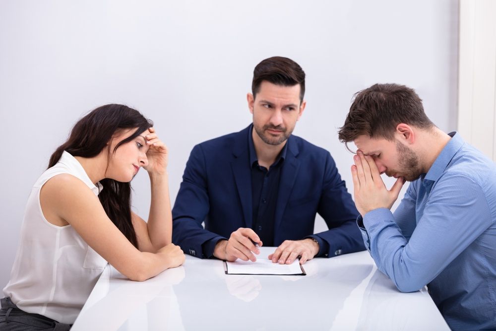 A Man and a Woman Are Sitting at a Table With a Lawyer — McVittie Legal In Ballina, NSW