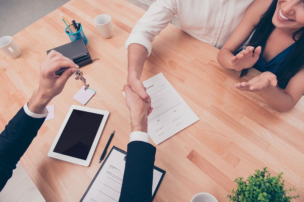 A Man is Shaking Hands With a Woman While Sitting at a Table — McVittie Legal In Ballina, NSW