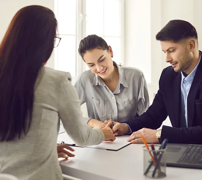 A Man and a Woman Are Signing Documents with A Lawyer — McVittie Legal In Ballina, NSW