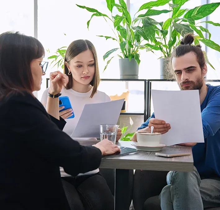 A Man and a Woman Are Reading Documents with A Lawyer — McVittie Legal In Ballina, NSW