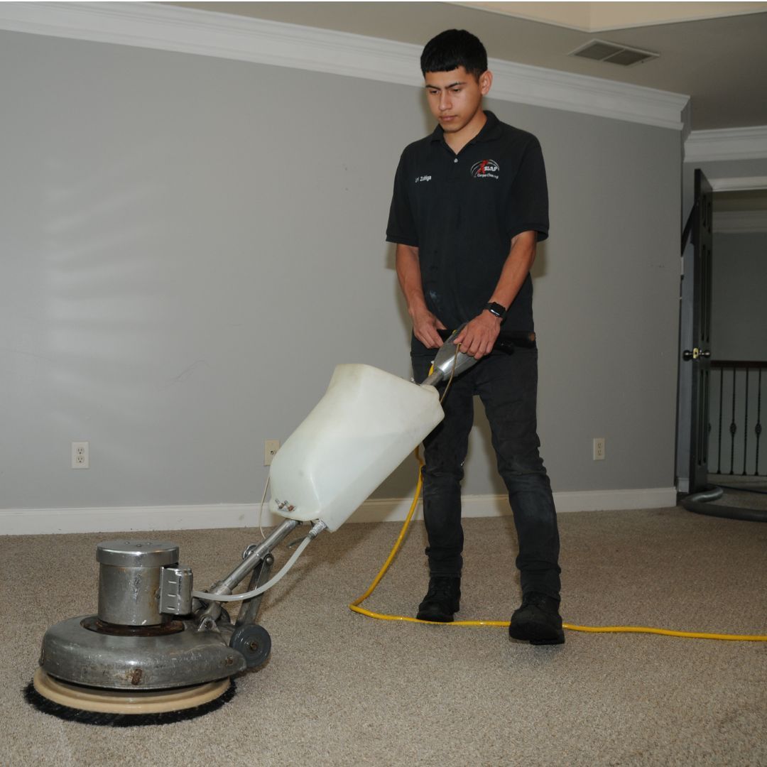 Professional shampoo carpet cleaning technician agitating stains from carpet.