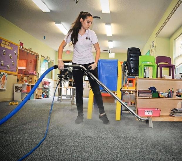 Professional carpet cleaning technician removing stains from carpet using the hot water extraction method.