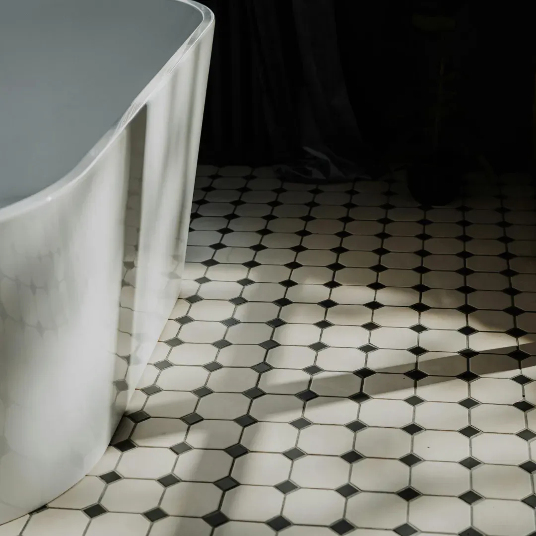 Ceramic tile flooring design with black and white patterns inside bathroom.