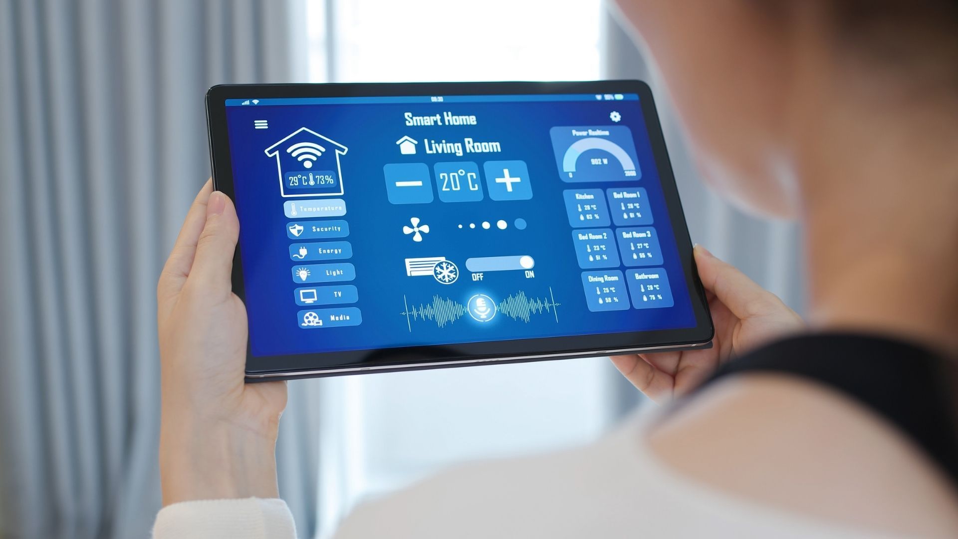 A woman is holding a tablet with a screen that says living room on it