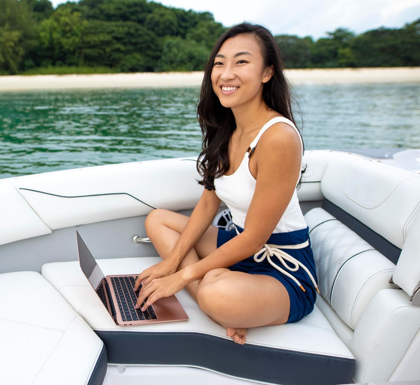 A woman is sitting on a boat using a laptop