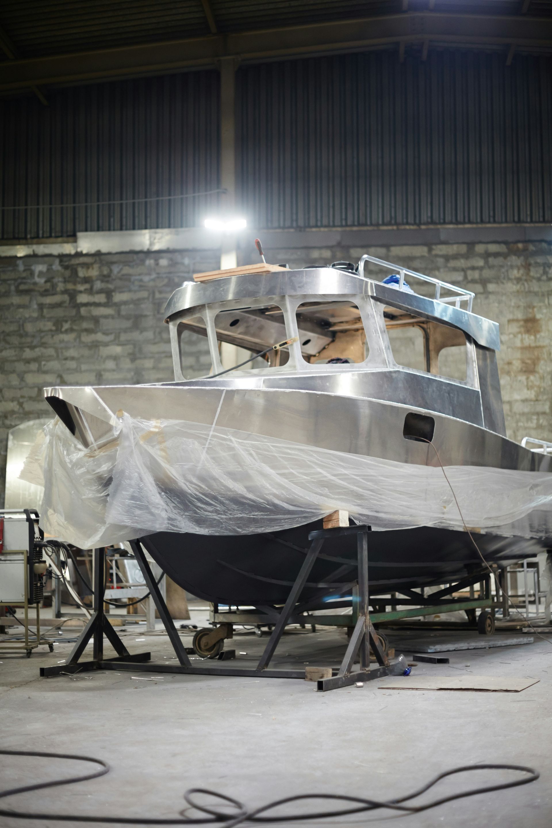 A stainless steel boat is being built in a warehouse.