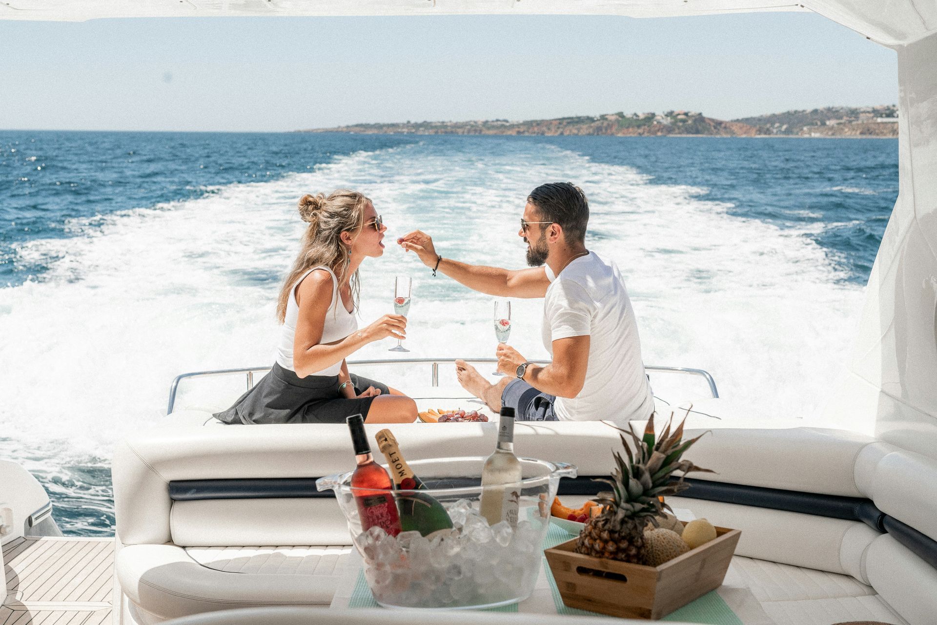 A man and a woman are drinking champagne on a boat in the ocean.