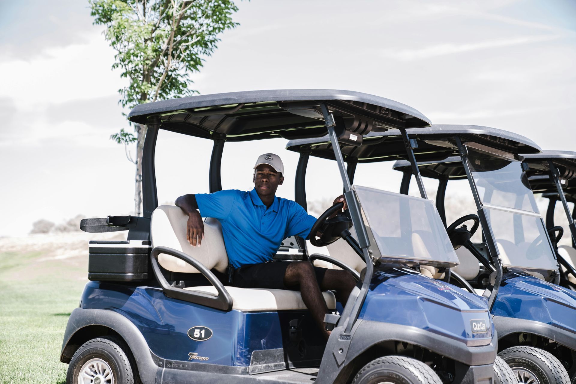 A man is sitting in a blue golf cart on a golf course.