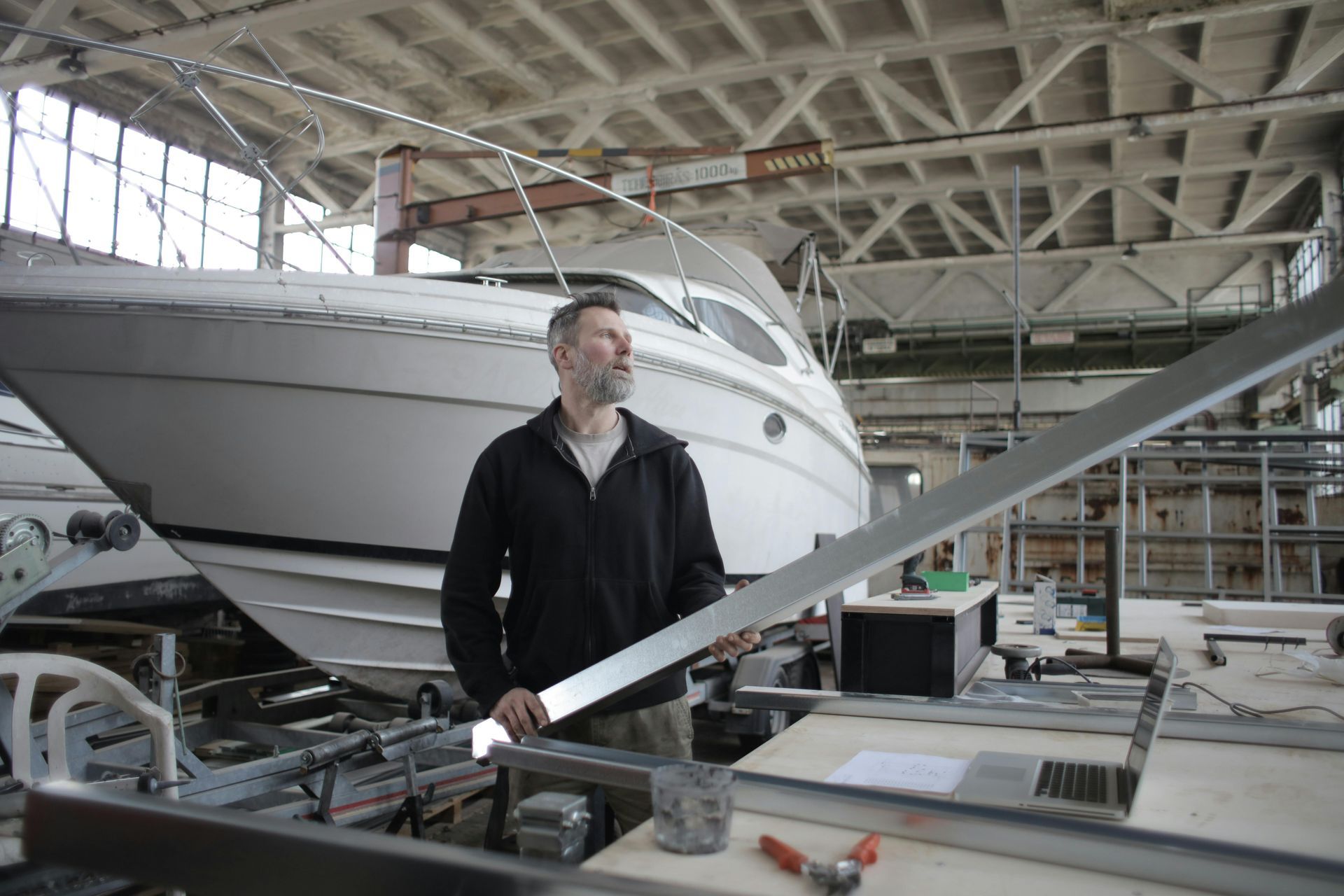 A man is standing in front of a boat in a factory.