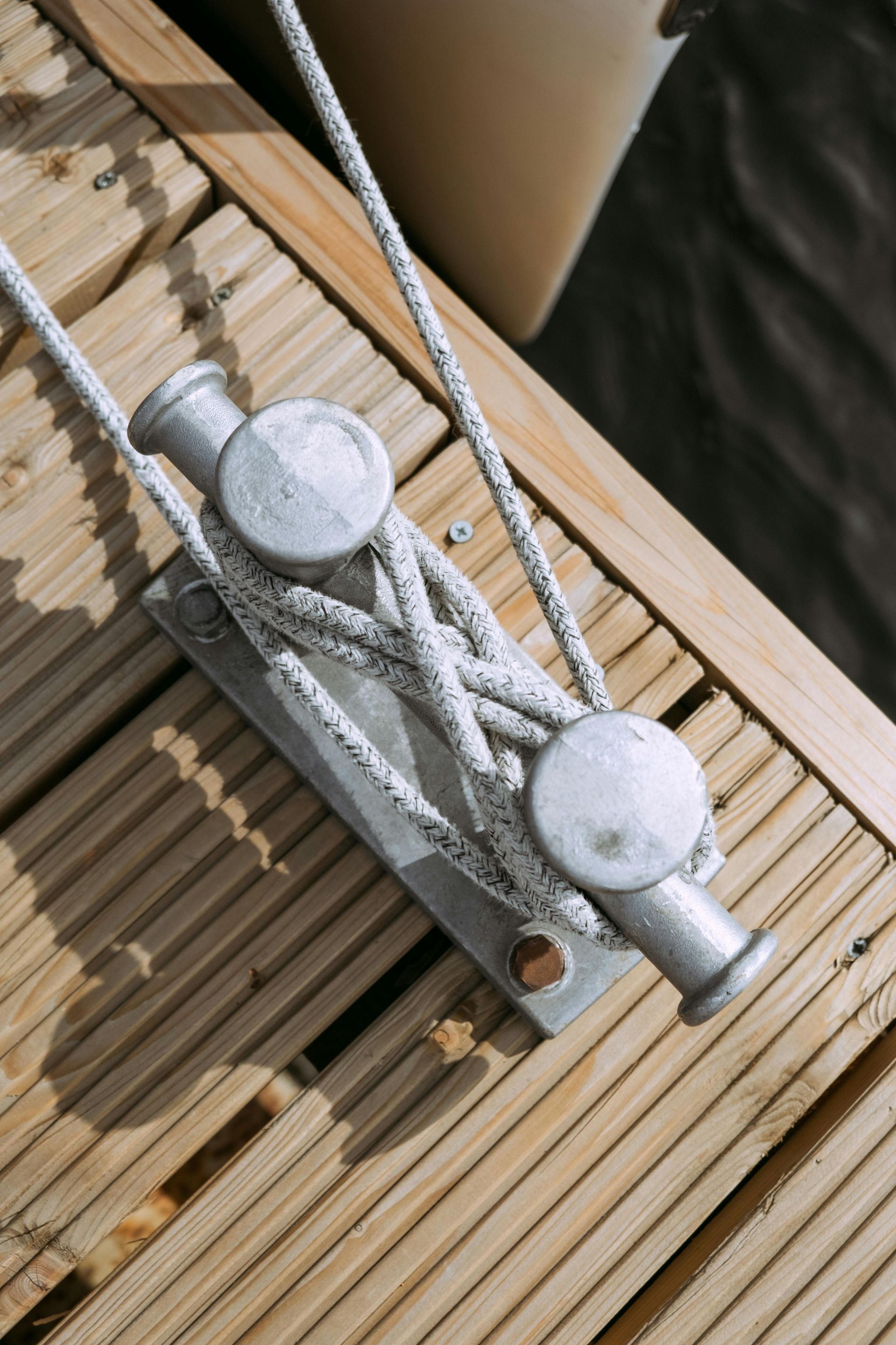 A rope is tied to a metal pole on a wooden deck.