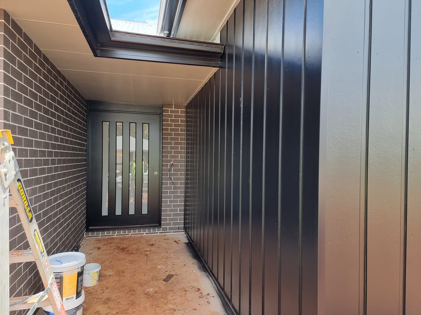 A Black Door Is Being Painted On The Side Of A House — LMS Painting & Maintenance Pty Ltd In Charlestown, NSW