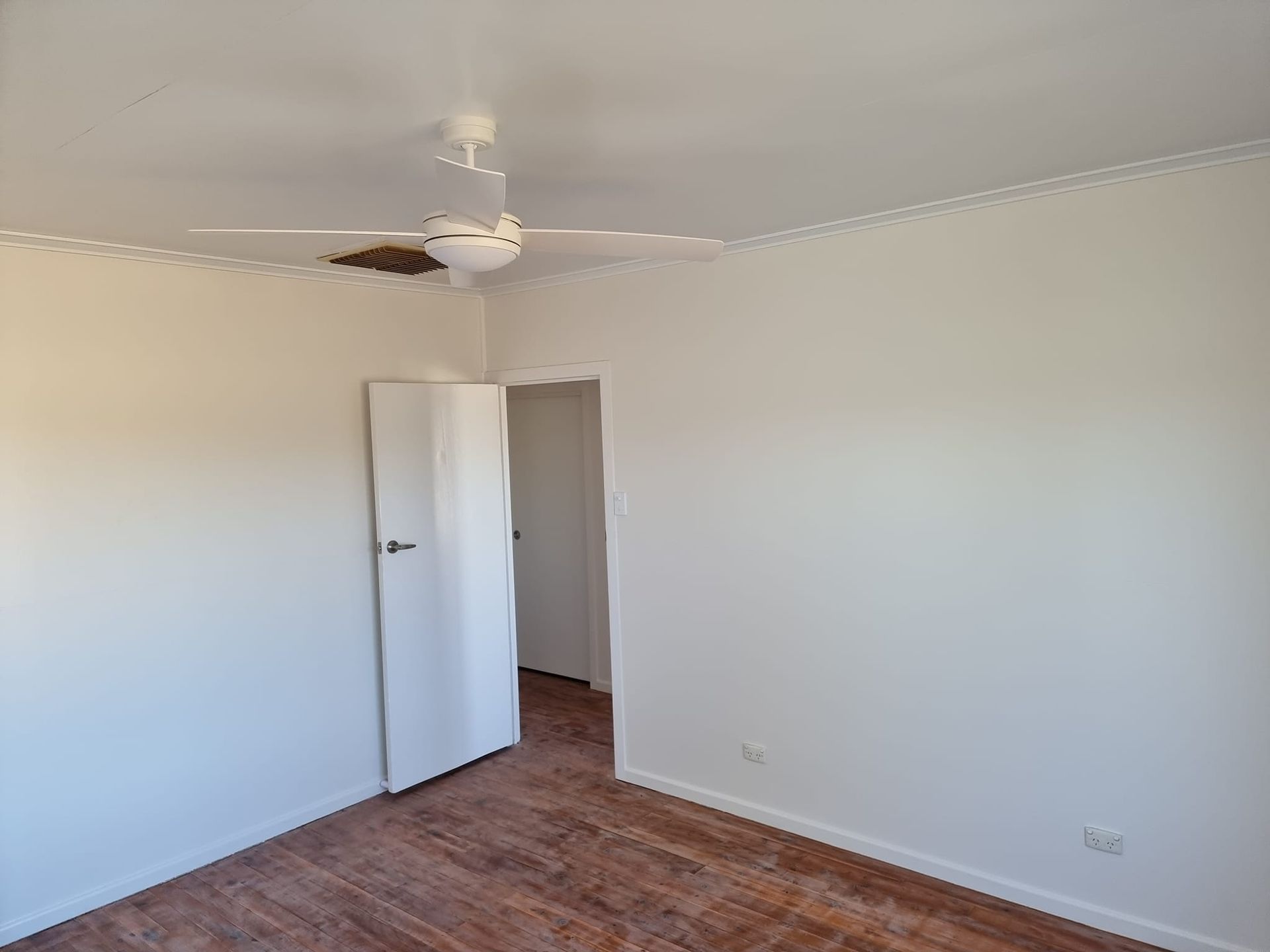 An Empty Room With A Ceiling Fan And A Door — LMS Painting & Maintenance Pty Ltd In North Lambton, NSW