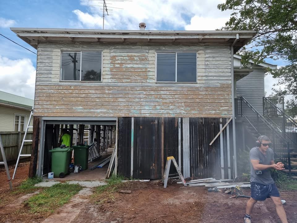 A Man Is Standing In Front Of A House That Is Being Remodeled — LMS Painting & Maintenance Pty Ltd In North Lambton, NSW