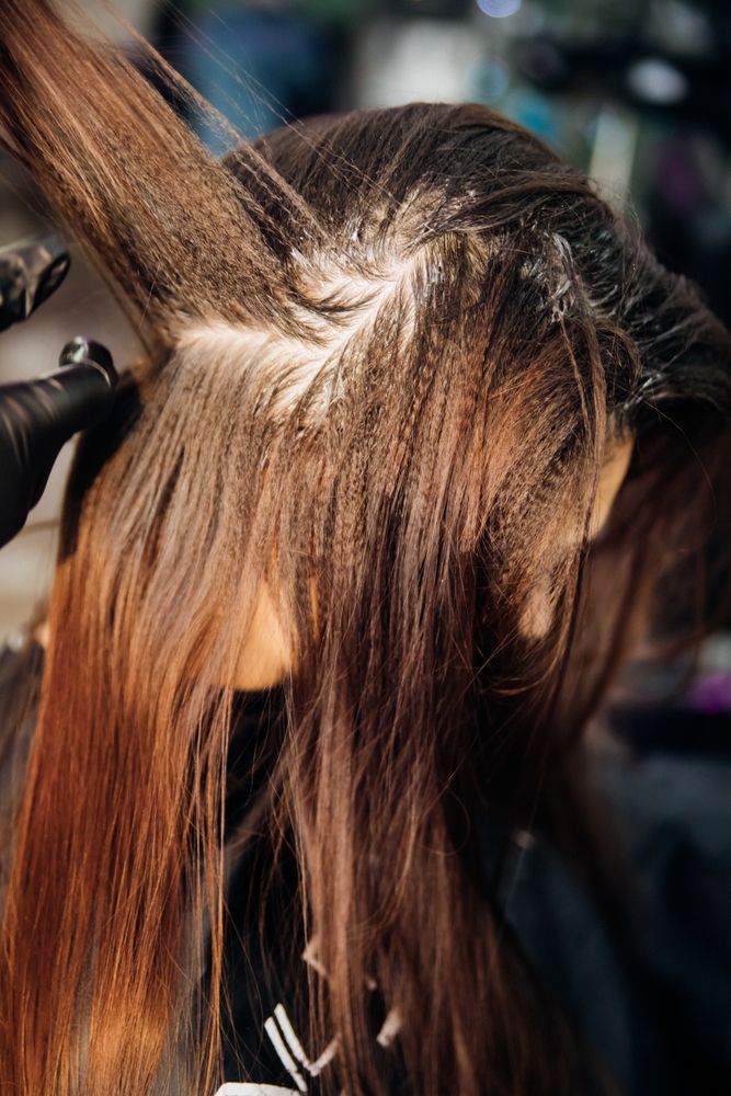 A woman is getting her hair dyed in a salon.