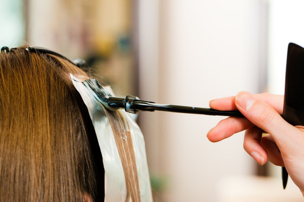 A woman is getting her hair colored by a hairdresser in a salon.