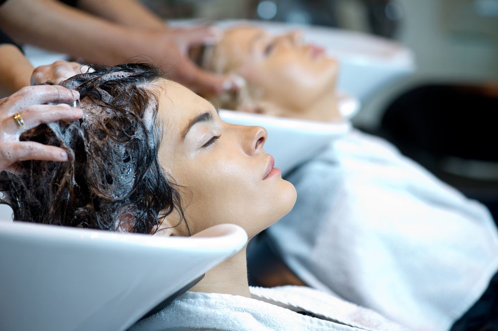 A woman is getting her hair treated by a hairdresser in a salon.