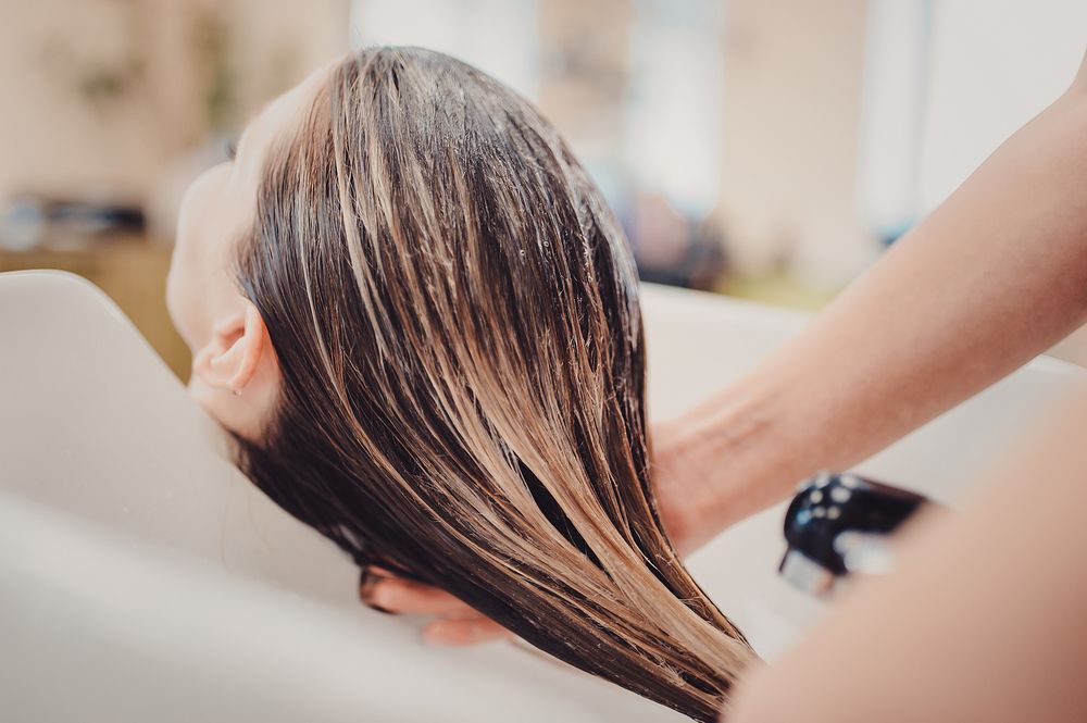 A woman is getting her hair washed in a sink at a salon.