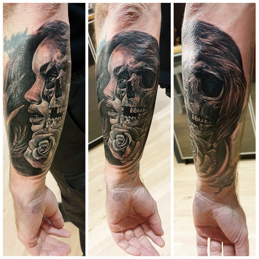 Een man heeft een tatoeage van het gezicht van een vrouw en een schedel op zijn onderarm
