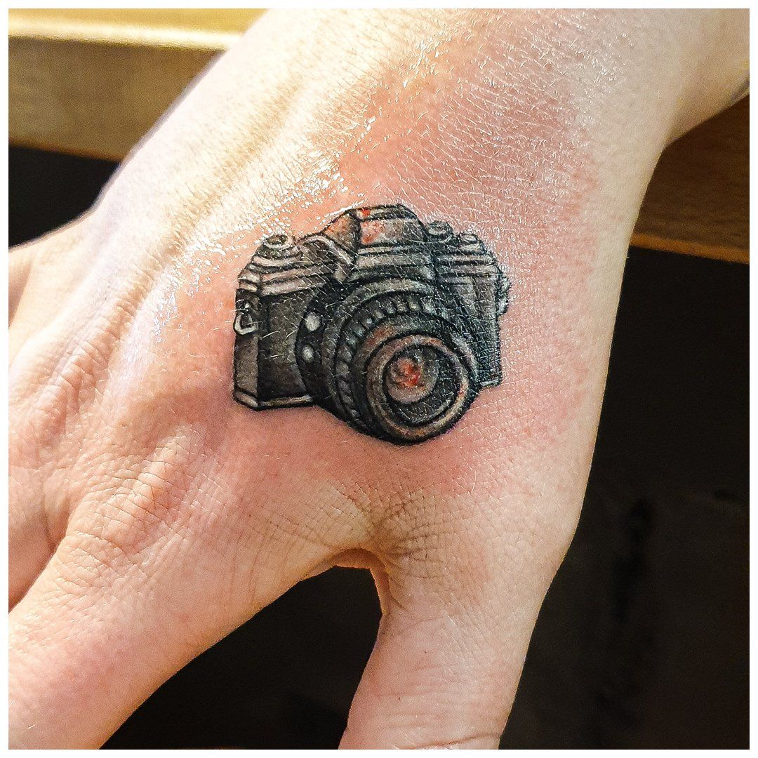 Een persoon heeft een tatoeage van een camera op zijn hand