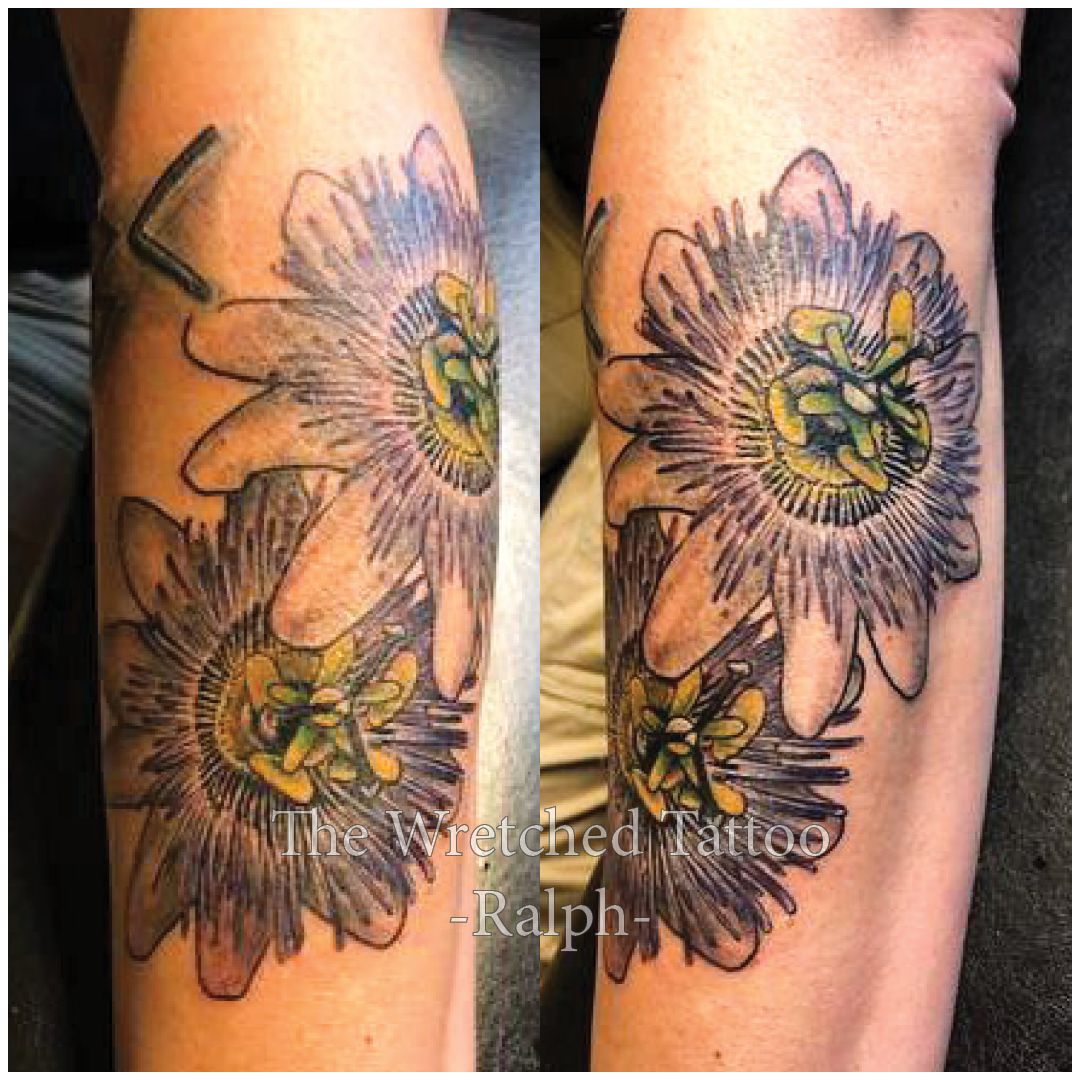 Een tatoeage van twee bloemen op iemands onderarm.