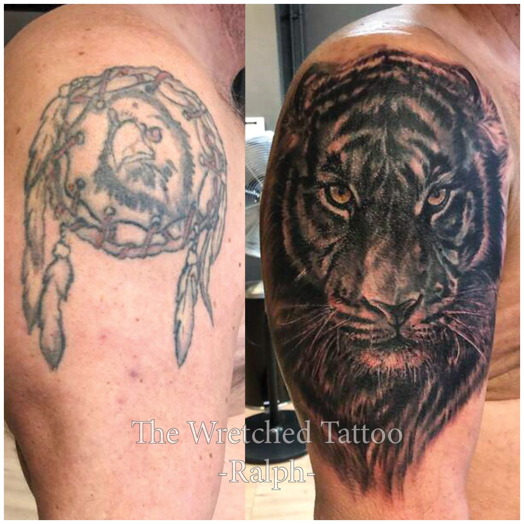 Een man heeft een tatoeage van een dromenvanger en een tijger op zijn arm.