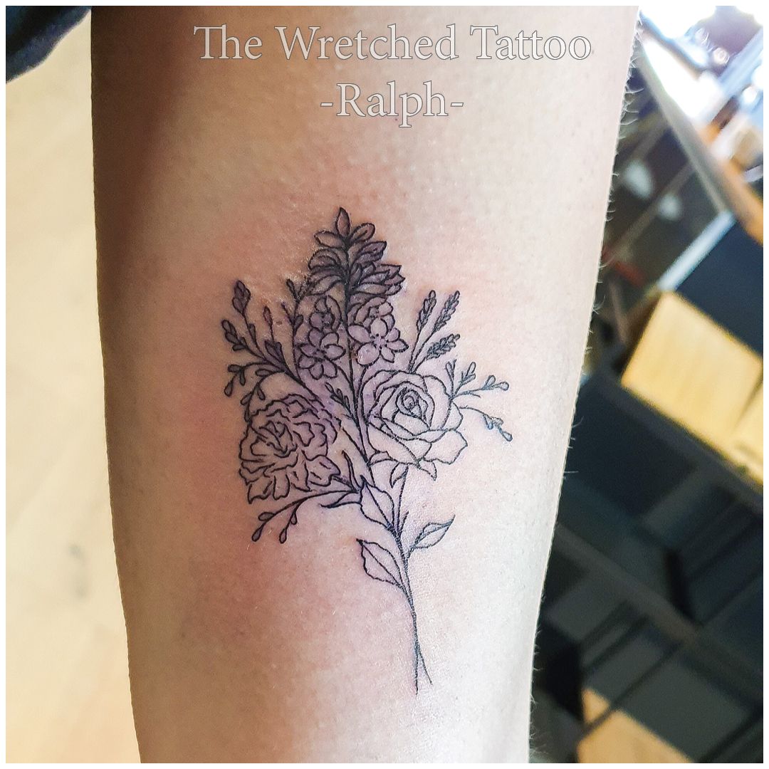 Een tatoeage van een boeket bloemen op iemands arm