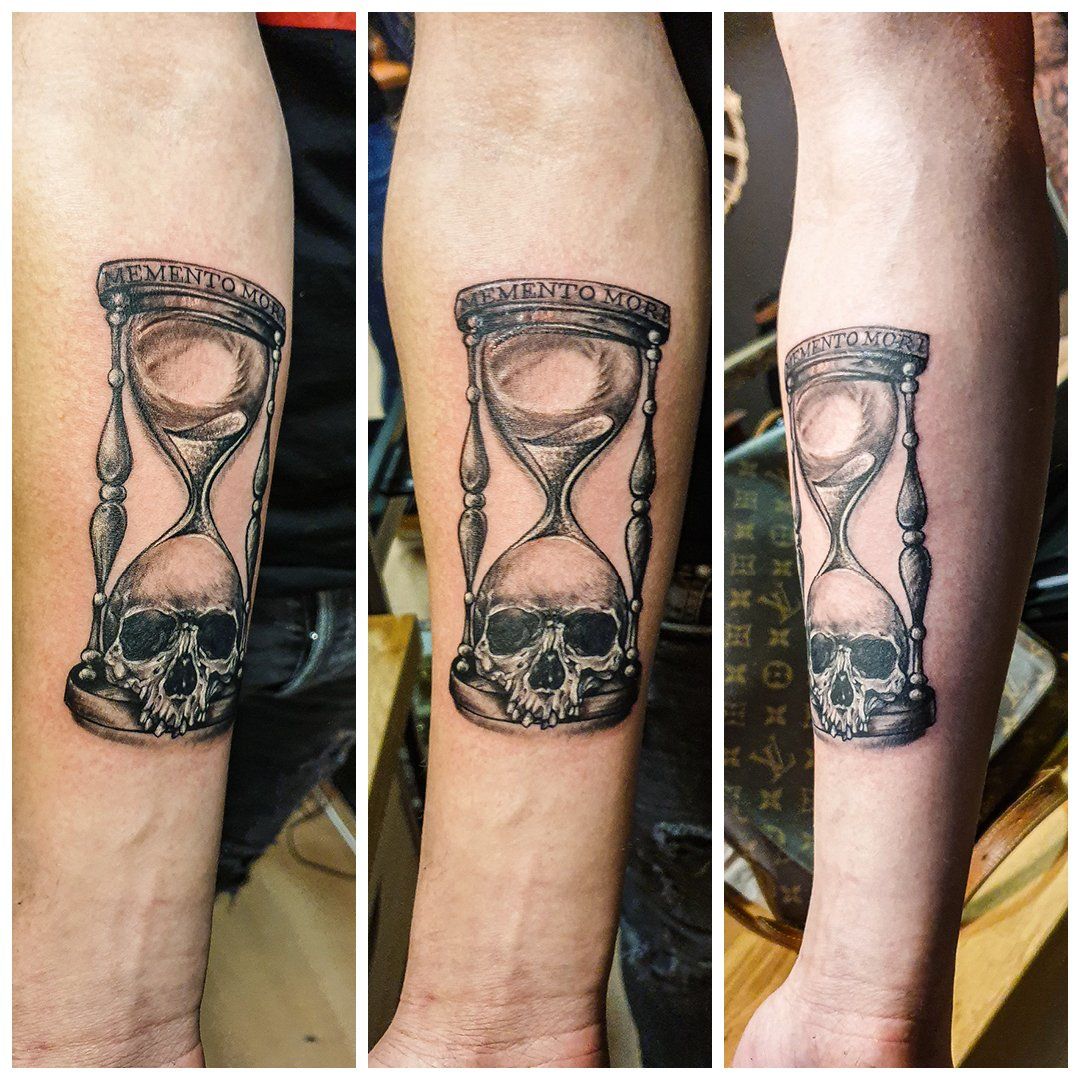 Een man heeft een tatoeage van een zandloper met een schedel erop.