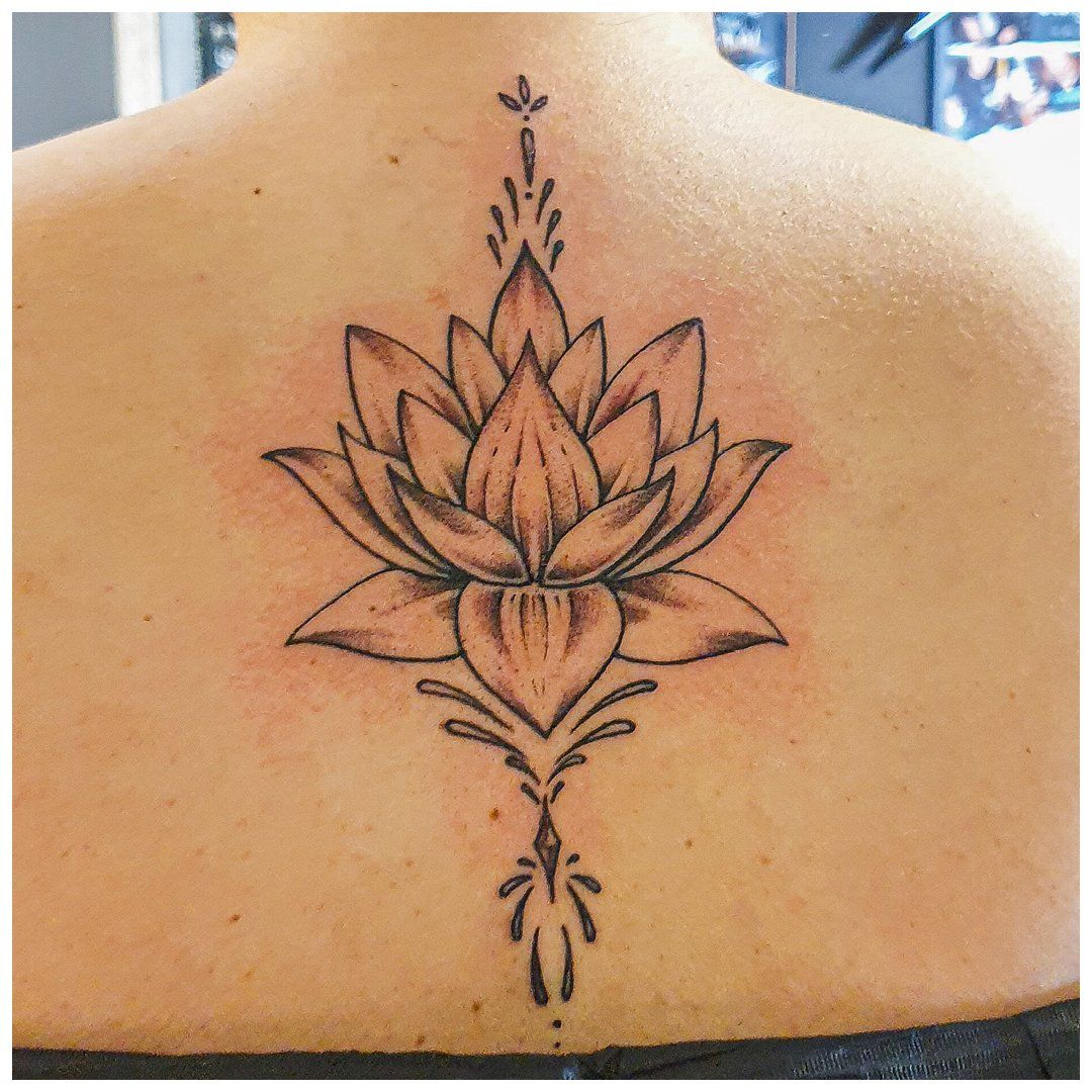 Een vrouw heeft een tatoeage van een lotusbloem op haar rug.