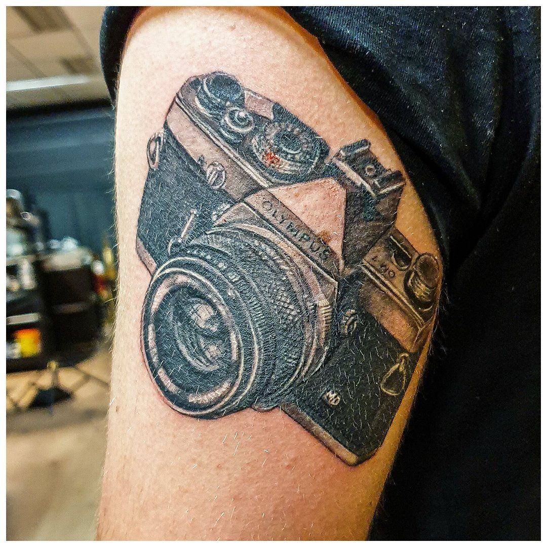 Een persoon heeft een tatoeage van een camera op zijn arm.