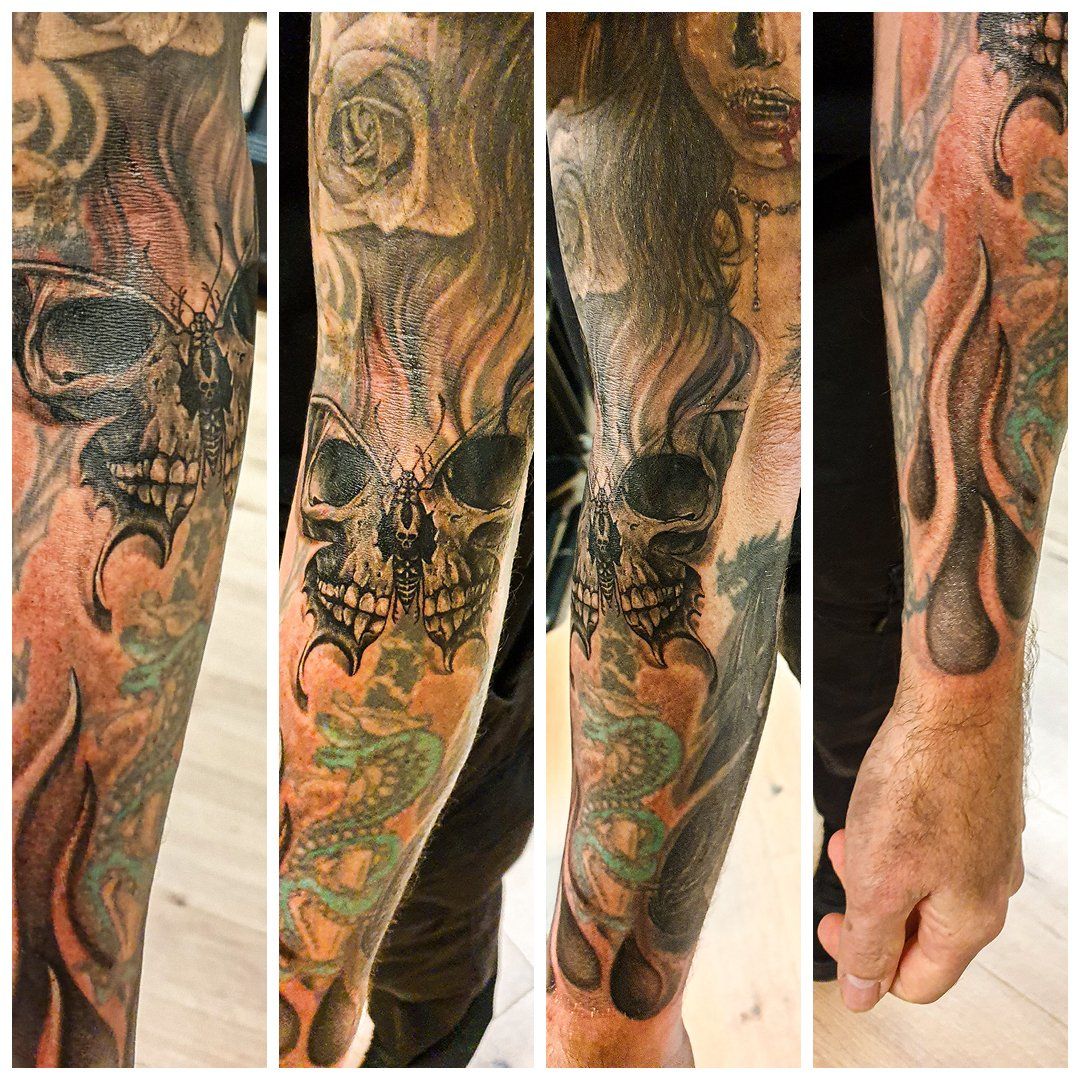 Een man heeft een tatoeage van een schedel en vlammen op zijn arm.