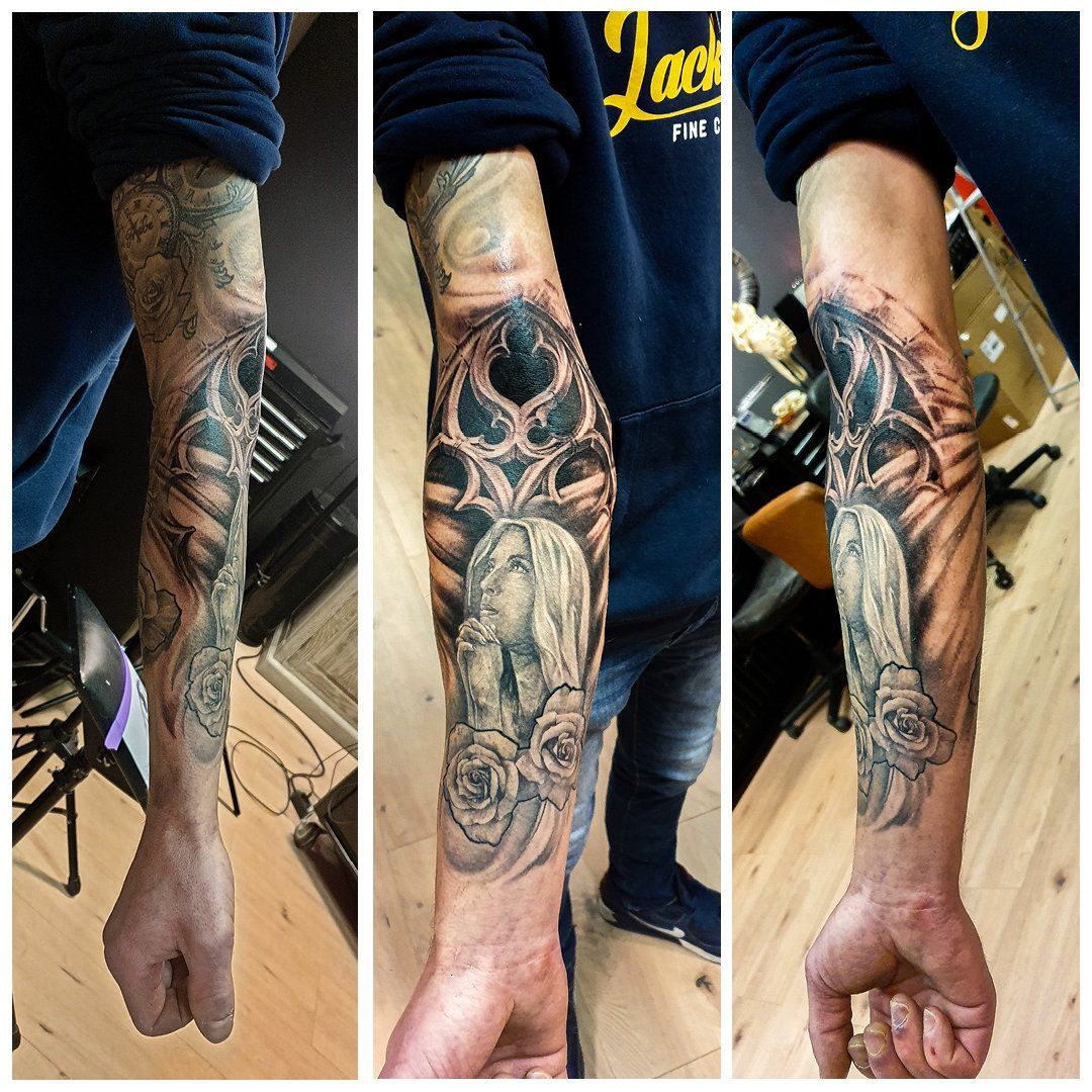 Een man heeft een tatoeage op zijn arm Van maria die bid met rozen en een kerk
