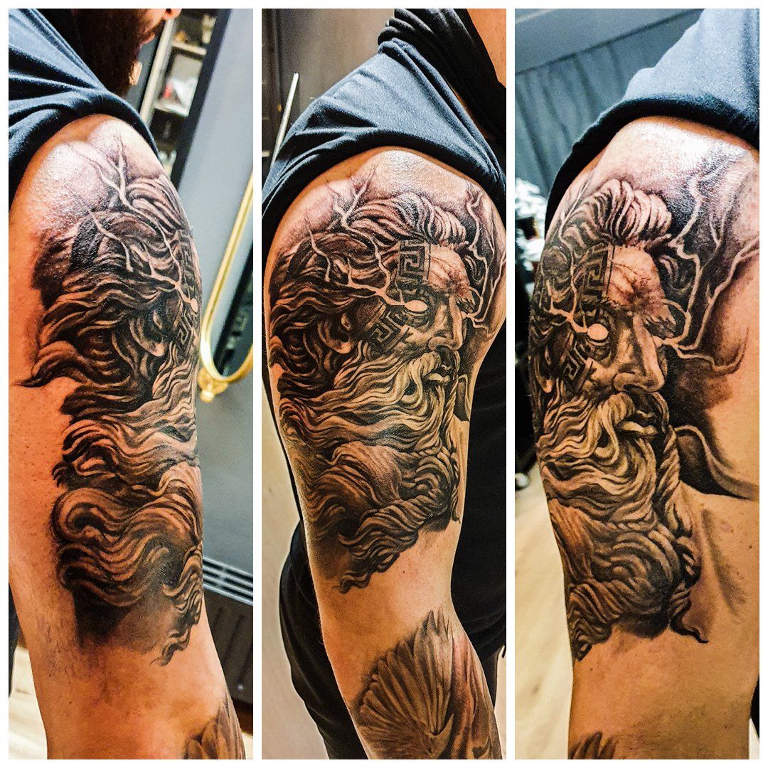 Een man heeft een tatoeage van een standbeeld op zijn arm.