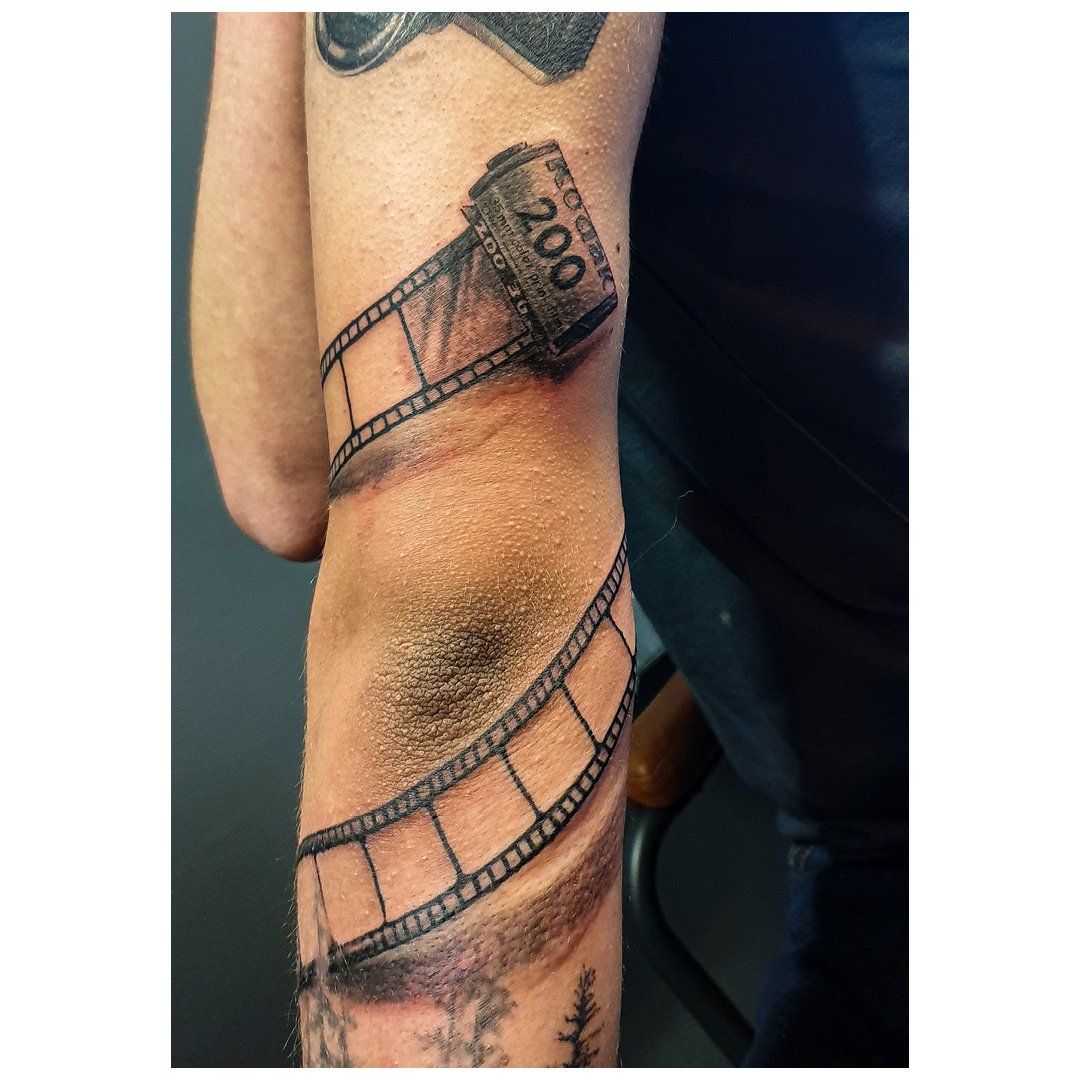 Een man heeft een tatoeage van een filmrolletje op zijn arm.