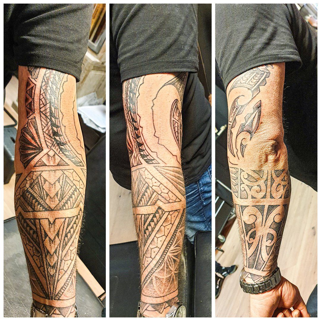 Een man met een tatoeage op zijn arm heeft een horloge om zijn pols