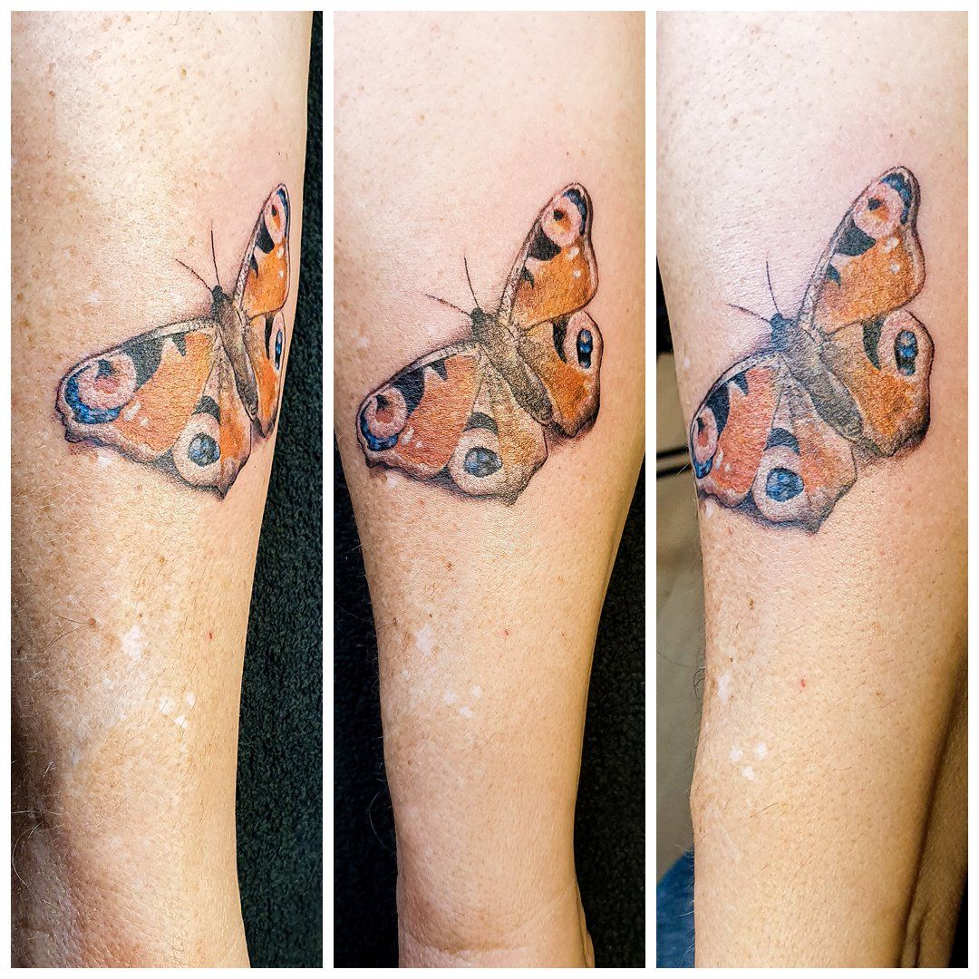 Een vrouw heeft een tatoeage van een vlinder op haar arm.