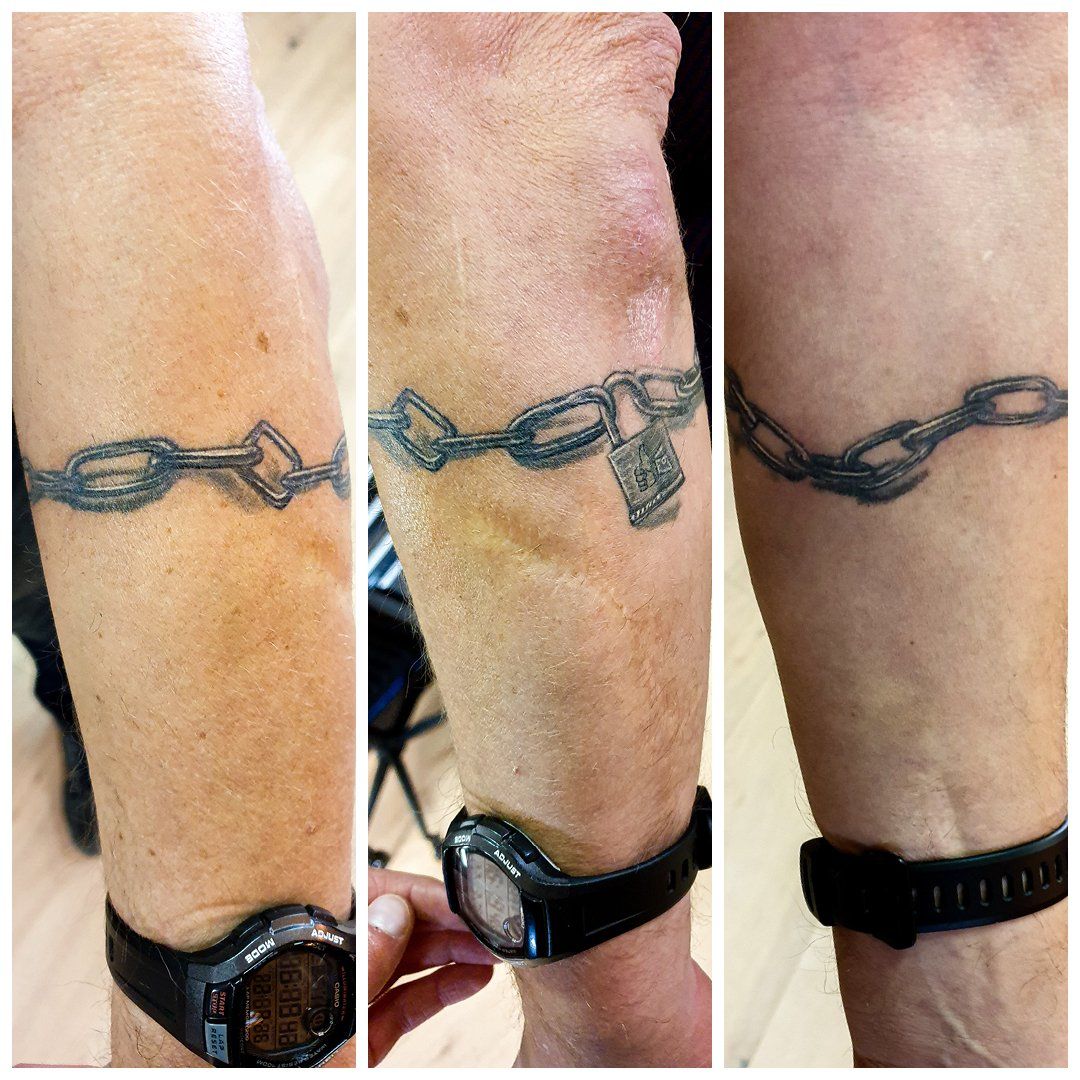Een persoon heeft een tatoeage van een ketting op zijn arm.